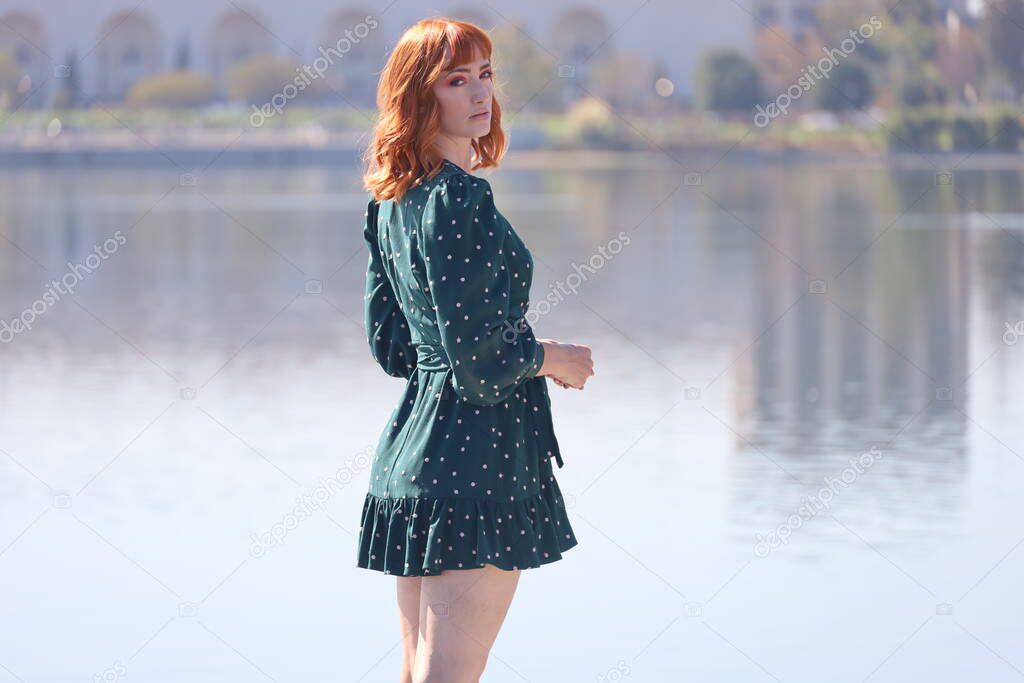 Photo of a Beautiful white girl in a beautiful dress standing in front of a lake
