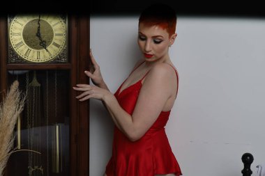 Güzel beyaz bir mankenin yatak odasındaki iç çamaşırlı bir saat önünde fotoğrafı.