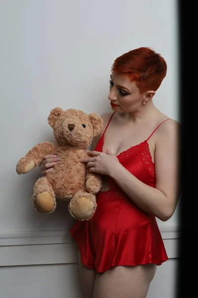 Photo of beautiful white model in a lingerie in a bedroomh olding a teddy bear