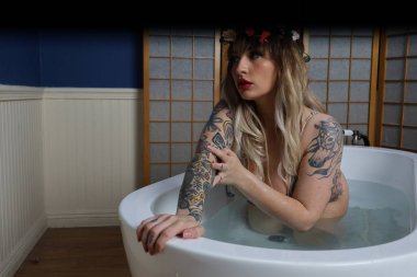 Küvette oturan güzel beyaz bir mankenin fotoğrafı.