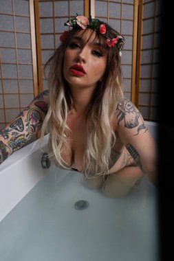 Küvette oturan güzel beyaz bir mankenin fotoğrafı.