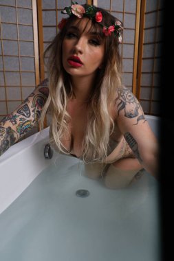 Küvette oturan güzel beyaz bir mankenin fotoğrafı.