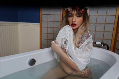 Küvette beyaz dantelli eşarp takan güzel beyaz bir mankenin fotoğrafı.