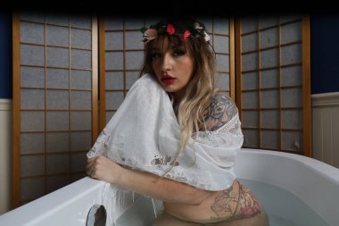 Küvette beyaz dantelli eşarp takan güzel beyaz bir mankenin fotoğrafı.