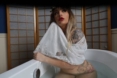 Küvette beyaz dantelli eşarp takan güzel beyaz bir mankenin fotoğrafı.