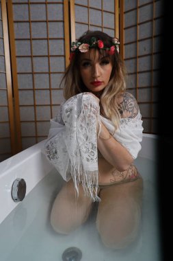 Küvette beyaz dantelli eşarp takan güzel beyaz bir mankenin fotoğrafı.