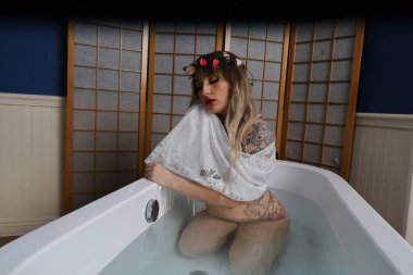 Küvette beyaz dantelli eşarp takan güzel beyaz bir mankenin fotoğrafı.