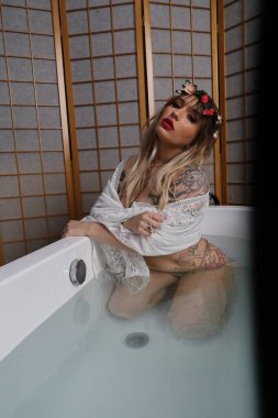 Küvette beyaz dantelli eşarp takan güzel beyaz bir mankenin fotoğrafı.