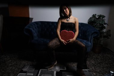 Kanepede kırmızı kalpli ve siyah dantelli güzel bir Vietnamlı mankenin fotoğraf çekimi.