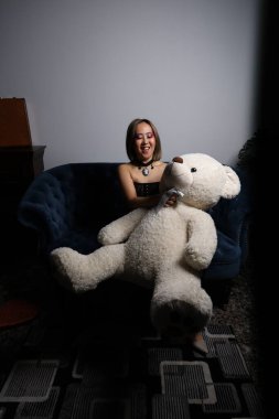 Kanepede oyuncak ayıyla güzel bir Vietnamlı mankenin fotoğrafı.