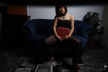 Kanepede kırmızı kalpli ve siyah dantelli güzel bir Vietnamlı mankenin fotoğraf çekimi.