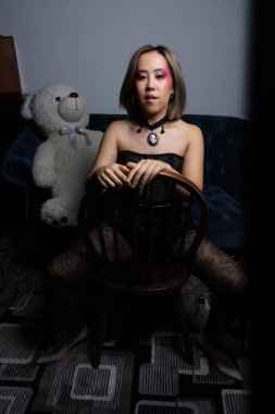 Kanepede oyuncak ayıyla güzel bir Vietnamlı mankenin fotoğrafı.