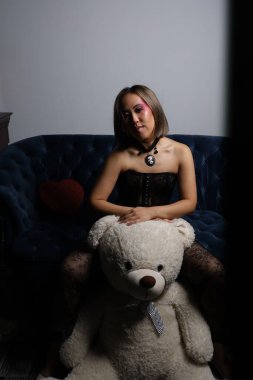 Kanepede oyuncak ayıyla güzel bir Vietnamlı mankenin fotoğrafı.