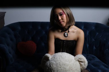 Kanepede oyuncak ayıyla güzel bir Vietnamlı mankenin fotoğrafı.