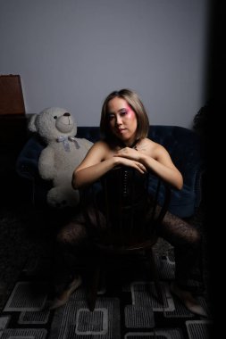 Kanepede oyuncak ayıyla güzel bir Vietnamlı mankenin fotoğrafı.