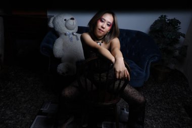 Kanepede oyuncak ayıyla güzel bir Vietnamlı mankenin fotoğrafı.