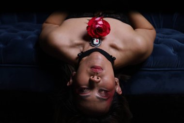 Güzel bir Vietnamlı mankenin elinde gülle kanepede otururken çekilmiş fotoğrafı.