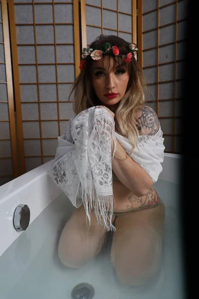 Küvette beyaz dantelli eşarp takan güzel beyaz bir mankenin fotoğrafı.