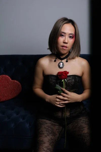 一个漂亮的越南模特拿着玫瑰坐在沙发上的照片 — 图库照片