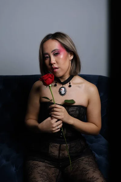 一个漂亮的越南模特拿着玫瑰坐在沙发上的照片 — 图库照片