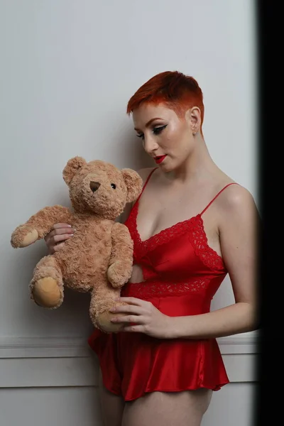 Photo of beautiful white model in a lingerie in a bedroomh olding a teddy bear