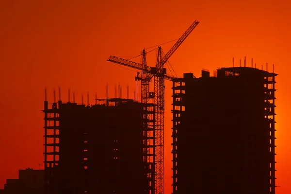 Guindastes e construção em construção contra o céu à noite — Fotografia de Stock