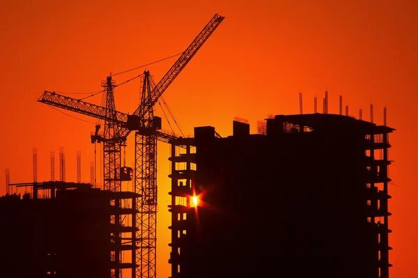 Kräne und Gebäude im Bau gegen den Abendhimmel — Stockfoto
