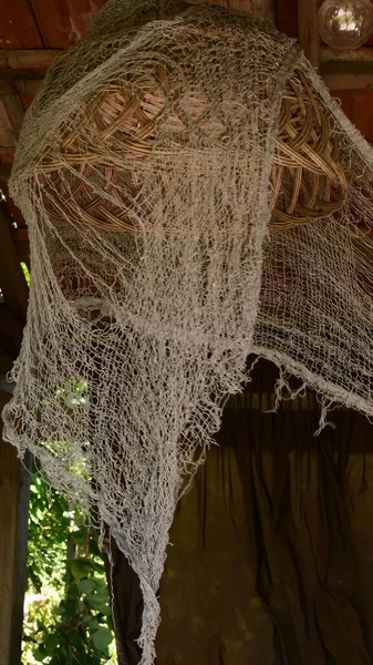 Old wicker lampshade and torn net look like in haunted house. Halloween decor