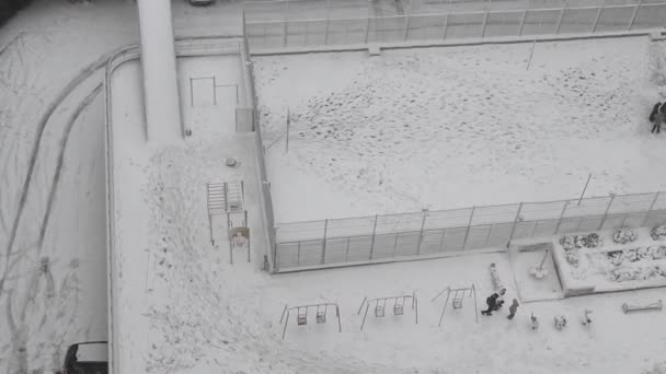 Vue du dessus de l'aire de jeux de condo avec des personnes méconnaissables marchant par la première couverture de neige — Video