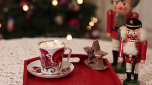 Retro nutcrackers and cup of marshmallow cacao on red tray with Christmas lights — Stockvideo