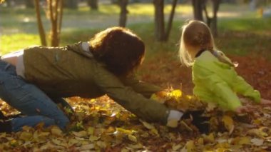 mutlu anne ve küçük kızı yavaş çekim dizi atmak sonbahar yaprakları.