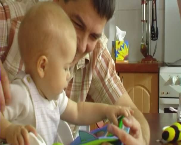 Vader met baby draai om de pagina's van het boek. — Stockvideo