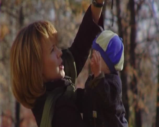 Den unga kvinnan promenader med barnet i park.anamorphic widescreen- — Stockvideo