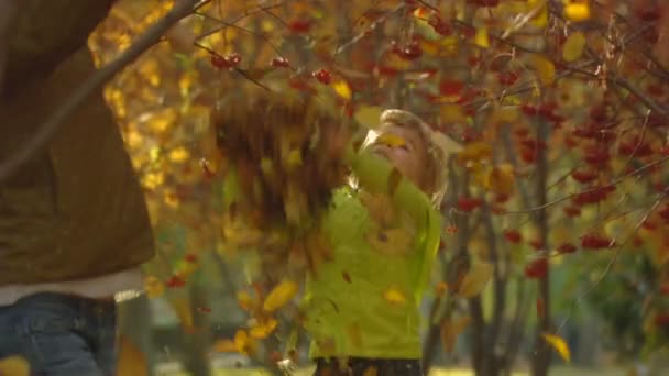 Secuencia de disparos en cámara lenta mamá feliz y la niña lanzar hojas de otoño . — Vídeos de Stock