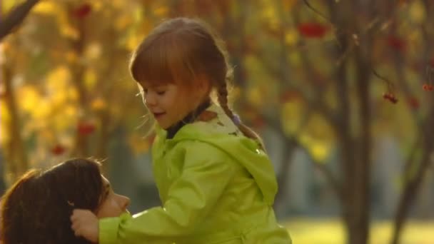 Sequência de tiros de câmera lenta da mãe feliz e a menina jogam folhas de outono . — Vídeo de Stock