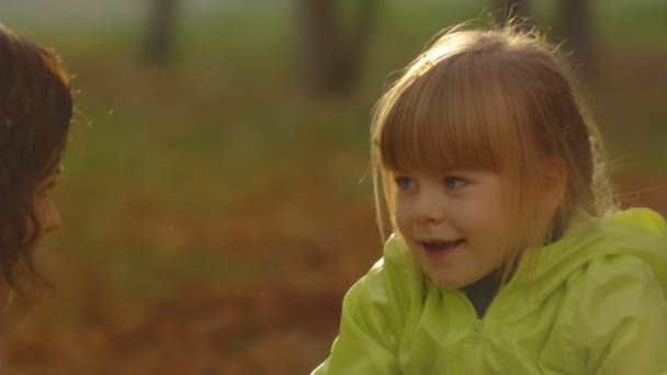 Volgorde van slow-motion shots van de gelukkige moeder en het kleine meisje gooien Herfstbladeren. — Stockvideo