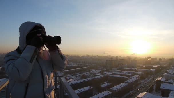 Фотограф работает на крыше небоскреба — стоковое видео