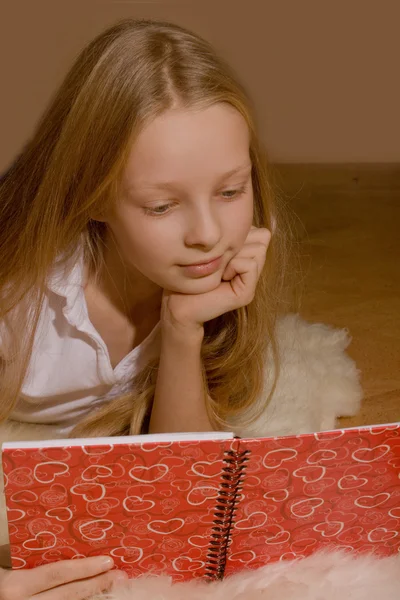 La niña con el pelo rubio está leyendo el libro — Foto de Stock