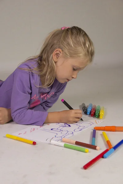 A menina com cabelo loiro desenha — Fotografia de Stock