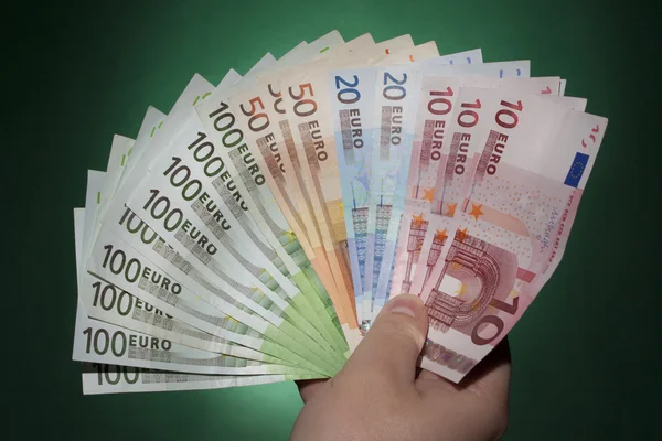 Mão de homem com euro sobre fundo verde — Fotografia de Stock