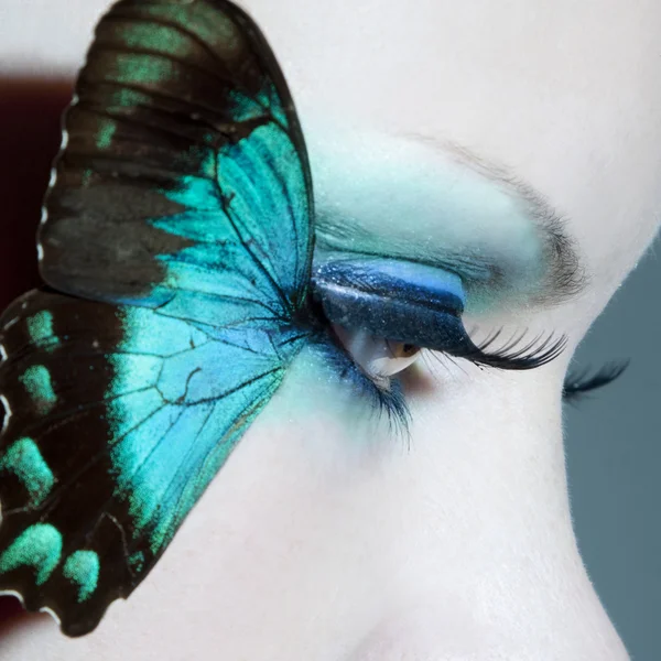 Mooie vrouw oog close-up met vlinder vleugels — Stockfoto