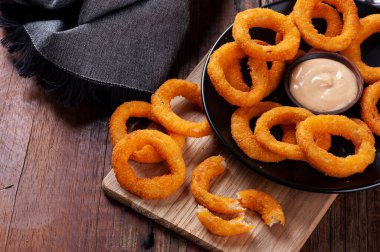 Baharatlı soslu ev yapımı lezzetli kızarmış soğan halkaları. Boşluğu kopyala
