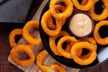 Lezzetli ev yapımı kızarmış soğan halkaları ve baharatlı sos.