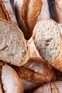 Çeşitli doğal mayalanmış ekmek türleri bir sepette bir arada. İçlerinden biri içini görmek için ikiye bölünmüş..