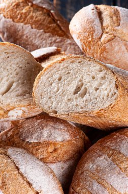 Çeşitli doğal mayalanmış ekmek türleri bir sepette bir arada. İçlerinden biri içini görmek için ikiye bölünmüş..