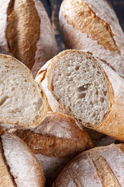 Çeşitli doğal mayalanmış ekmek türleri bir sepette bir arada. İçlerinden biri içini görmek için ikiye bölünmüş..