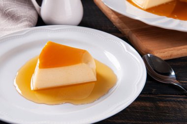 Beyaz tabakta lezzetli yoğunlaştırılmış sütlü puding. Özelleştirilmiş parça.