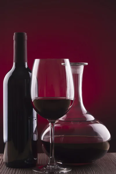 Copa y botella de vino sobre fondo rojo —  Fotos de Stock