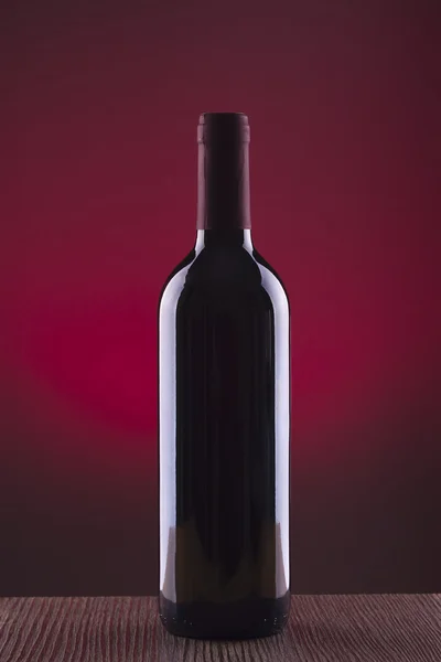 Glass and bottle of wine over red background — Stock Photo, Image