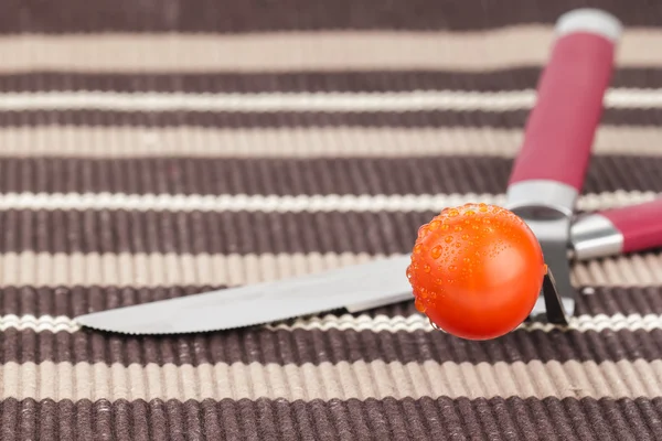 Tomate, Gabel und Messer auf einem Tischtuch — Stockfoto